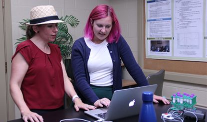 faculty member and a graduate student looking at a laptop